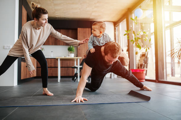 istock Father entertaining his baby while doing single arm plank at home 1216971791