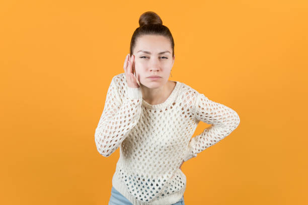 visually impaired girl peers at something visually impaired girl peers at something. Isolated on orange-yellow background squint eyes stock pictures, royalty-free photos & images