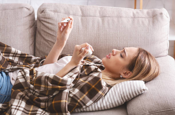 istock Got sick concept. Woman with thermometer and napkin 1216972739