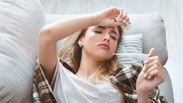 istock Girl with high temperature looks at thermometer 1216972816