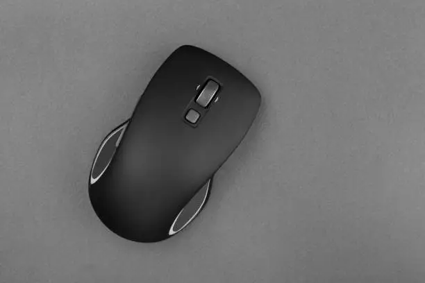 Photo of Wireless computer mouse in black on a gray background.