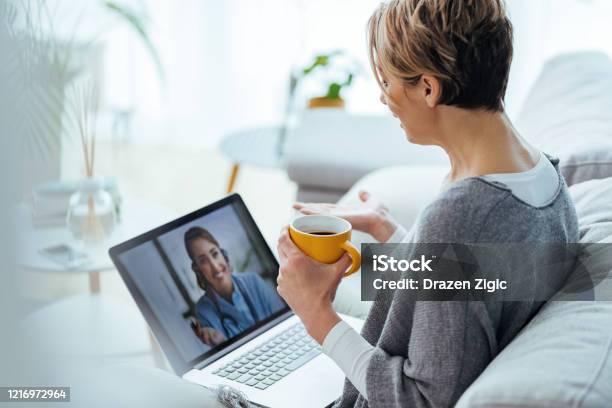 Frau Mit Laptop Und Videoanruf Mit Ihrem Arzt Während Zu Hause Sitzen Stockfoto und mehr Bilder von Telemedizin