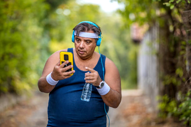 istock Obese man using phone after exercises in the park. 1216977927