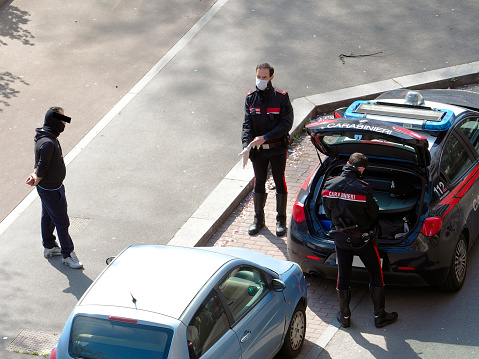 Milan, Italy, April 2020 - A patrol of Carabinieri (Italian paramilitary police) with medical mask and protective gloves controlling potential violation of the \