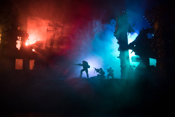 istock Army sniper with large caliber rifle standing in the fire and smoke. Backlit silhouette, toned image 1216980568