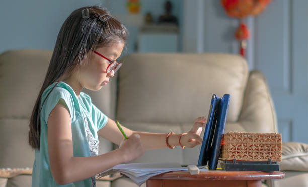 istock A young girl using digital device for online learning at home 1216980924