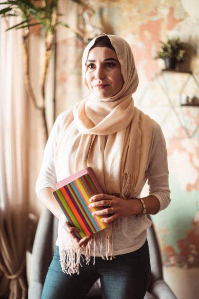 istock arab woman at home holding a book 1216982236