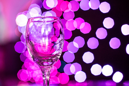 Wineglass in a nightclub with glitter bokeh background.