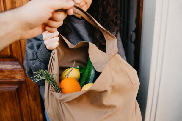 A man is delivering a bag of vegetables and fruit A man is delivering a bag of vegetables and fruit. Pov view of the man, giving the bag to a woman. passing giving photos stock pictures, royalty-free photos & images
