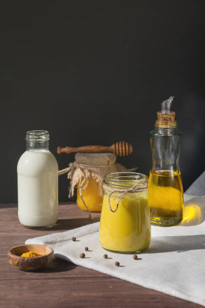 istock Turmeric-based golden milk healing drink and ingredients on black background. 1216989581