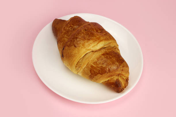 istock croissant in a white plate on a pink, colored background 1216991963