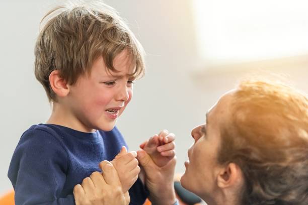 petit garçon pleurant étant consolé par sa mère - piquer une colère photos et images de collection