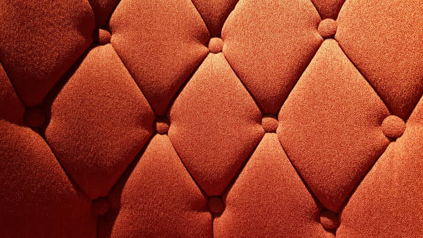 Orange color fabric surface of upholstered furniture. Rhombus pattern sofa tightened with round buttons on soft textile background. Interior upholstery. stock photo
