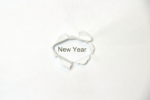 Word new year on white isolated background, the inscription through the wound hole in the paper. Stock photo for web and print with empty space for text and design.