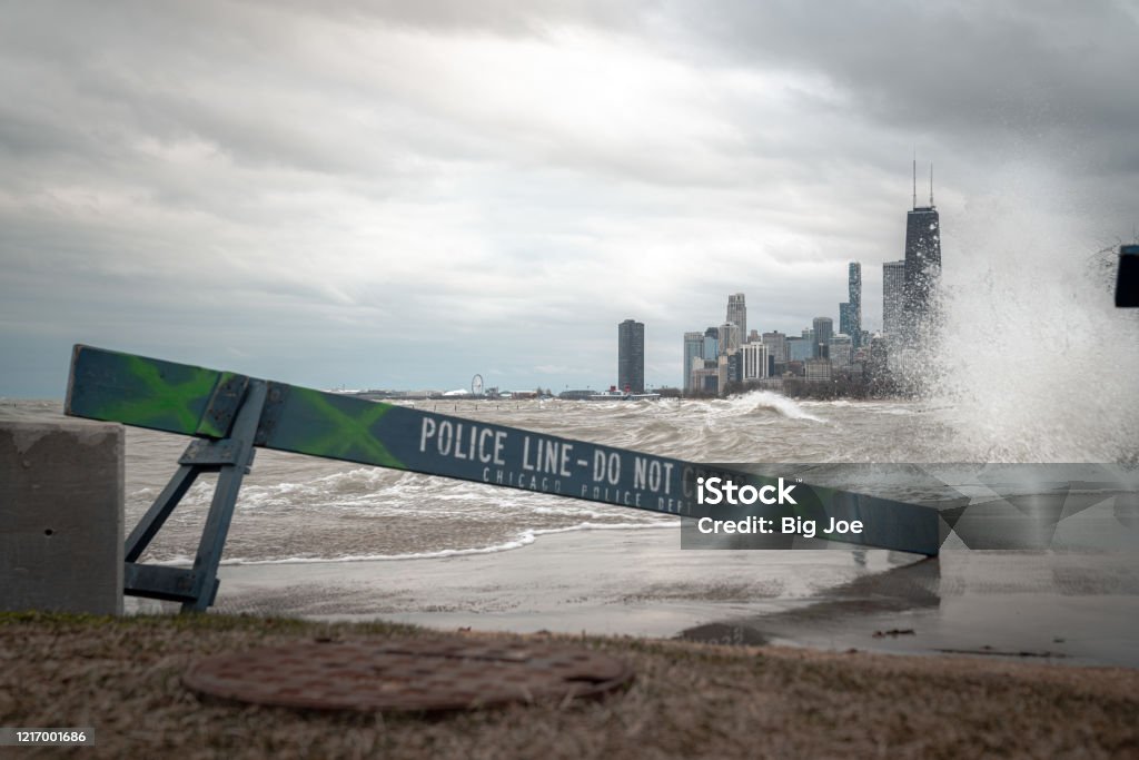 Chicago skyline view with blue wooden police barricades blocking off the lakefront trail or bike path due to high winds and dangerous waves crashing into the shore which are eroding the coastline. Architecture Stock Photo Chicago skyline view with blue wooden police barricades blocking off the lakefront trail or bike path due to high winds and dangerous waves crashing into the shore which are eroding the coastline. Architecture Stock Photo