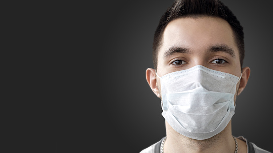 Una persona usa una máscara protectora para prevenir la propagación de la infección por coronavirus en el aire 2019-nCov. Foto de estudio, banner, sobre un fondo oscuro. photo