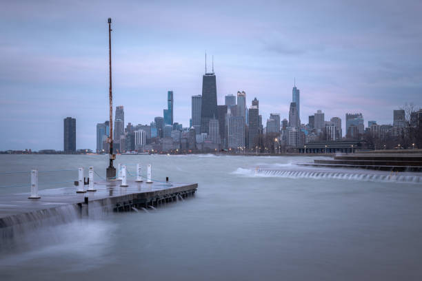 fantastic cityscape panoramic skyline view of chicago from fullerton avenue during a windy day with water cascading over a concrete pier at night just after sunset as lights begin to turn on in city. - day to sunset imagens e fotografias de stock