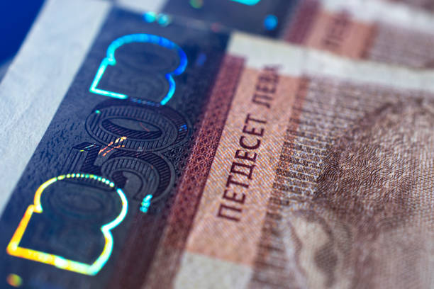 Macro close-up of bulgarian banknotes from fifty leva and bulgarian coins from one and two leva. The banknotes are on a dark surface.
