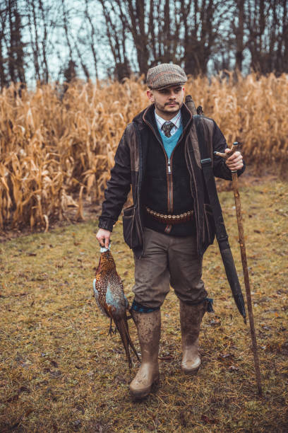 Hunter carrying pheasants walking towards camera