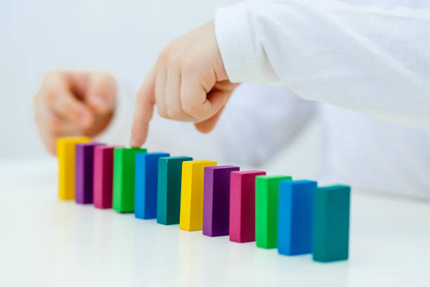 Building items in a single row. Concept of diagnostics of children's autism. A child plays with a colored wooden construction tool. Close. Building items in a single row. Concept of diagnostics of children's autism. A child plays with a colored wooden construction tool. Close. pileup stock pictures, royalty-free photos & images