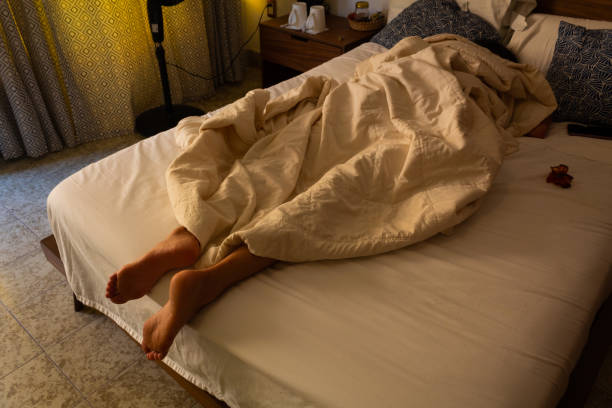 istock Feet on a white bed covered with white bed sheets, concept of sleep, rest and relaxation 1217006067