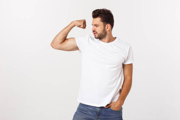 istock Handsome fit young funny bearded man pointing to his bicep and smiling on white background 1217009034