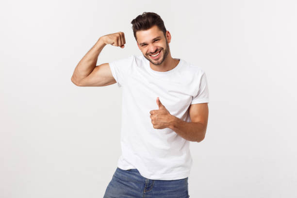 istock Handsome fit young funny bearded man pointing to his bicep and smiling on white background 1217009069