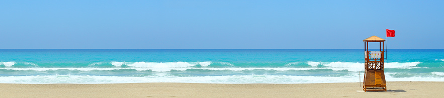 Wooden lifeguard tower on the beach on a background of sea and blue sky, panorama.