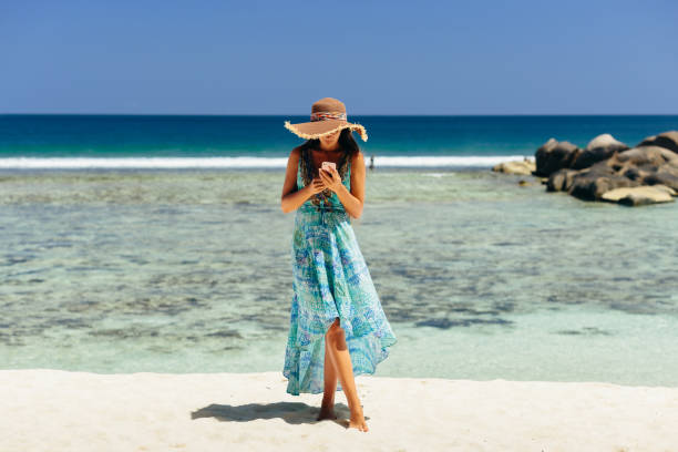 istock woman holding smartphone on beach 1217010511