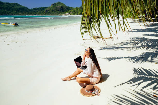 istock Remote working woman on beach in tropics 1217010585