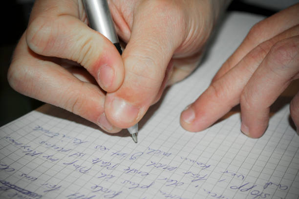 Closeup on a man's hand writing on toilet paper with a pencil