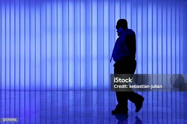 Silhueta De Homem De Negócios Preto Contra Parede De Luz Azul Moderno - Fotografias de stock e mais imagens de Adulto