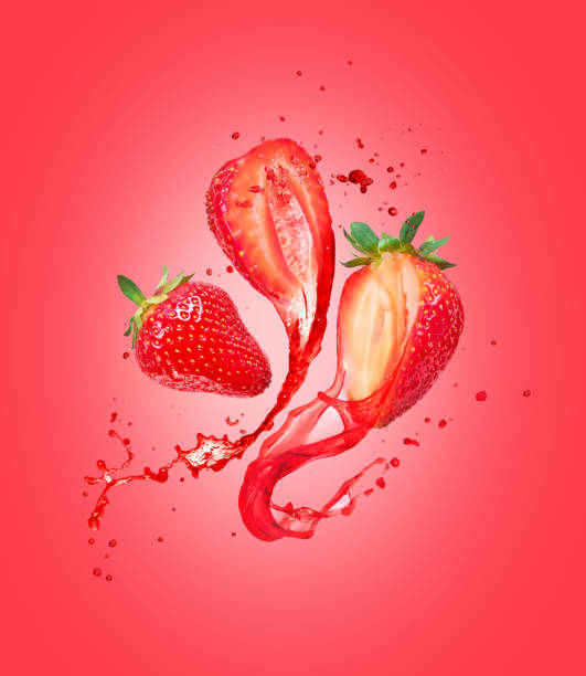 istock Juice splashes out from cutted strawberries on a red background 1217011759