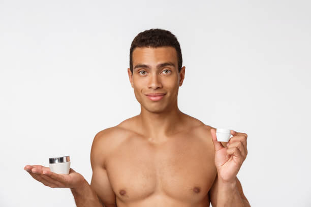 foto di un uomo afro-americano a torso libero che sorride e tiene la crema isolata su sfondo bianco - hairy men shaving chest foto e immagini stock