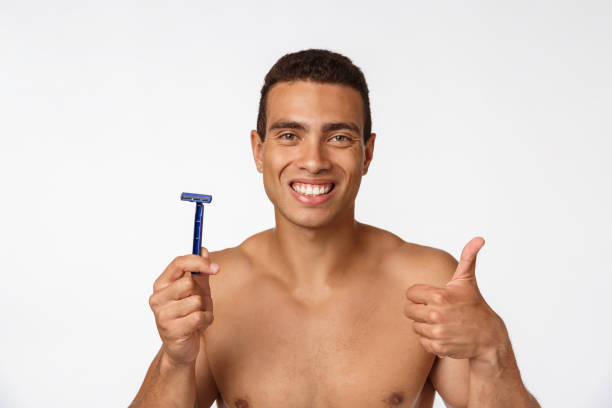 primo piano di un uomo africano nudo felice che tiene il rasoio isolato su sfondo grigio. - hairy men shaving chest foto e immagini stock