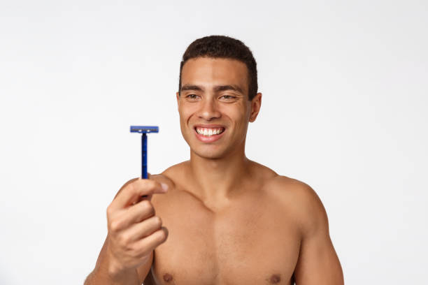 primo piano di un uomo africano nudo felice che tiene il rasoio isolato su sfondo grigio. - hairy men shaving chest foto e immagini stock
