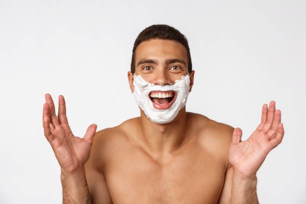 primo piano di un uomo africano nudo felice con il viso in schiuma da barba isolato su sfondo grigio - hairy men shaving chest foto e immagini stock