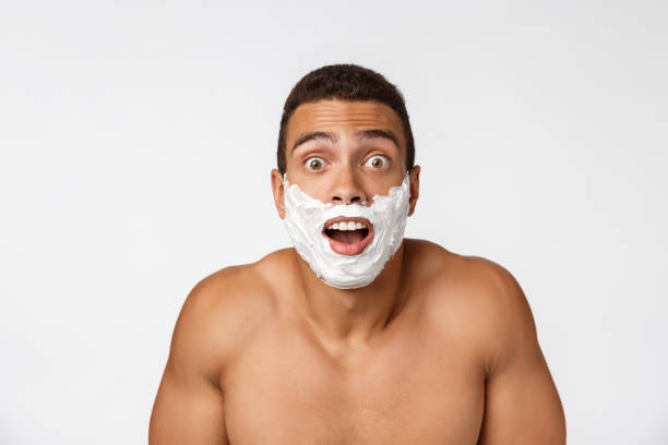 primo piano di un uomo africano nudo felice con il viso in schiuma da barba isolato su sfondo grigio - hairy men shaving chest foto e immagini stock