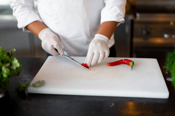 istock Unrecognizable young African chef standing in professional kitchen in restaurant preparing a meal of meat and cheese vegetables. 1217012849
