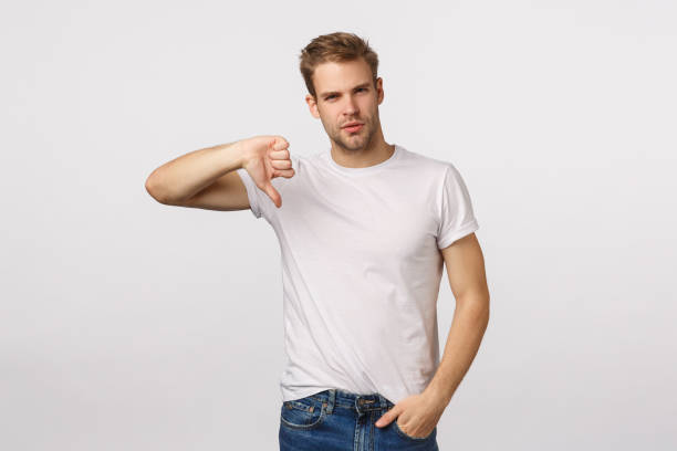 istock Serious-looking, skeptical and judgemental handsome blond bearded guy show thumb-down and looking disappointed, give negative feedback, upset with poor results, judging, white background 1217013651