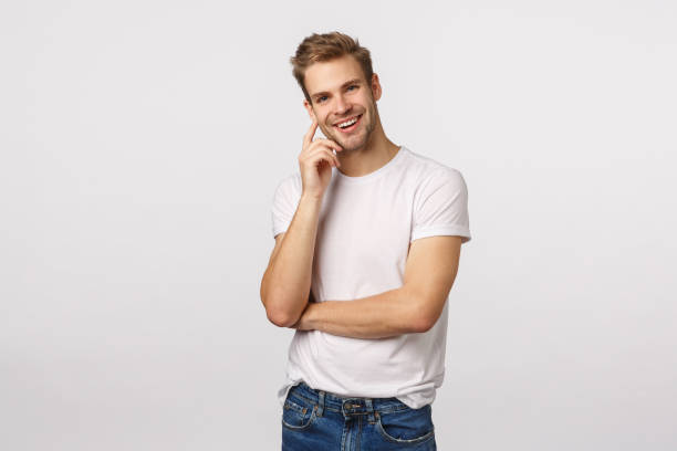 istock Charming handsome smiling blond caucasian man grinning at camera, touching cheek and tilt head as listening interesting story, agree with friend, like what hear, standing pleased white background 1217014324