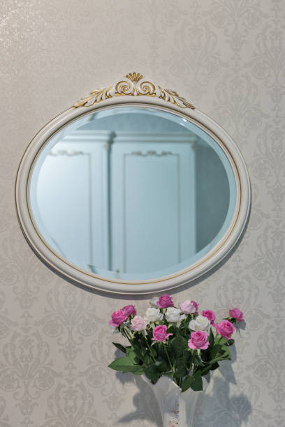 istock Round mirror on the wall and flowers multicolored installation 1217018260