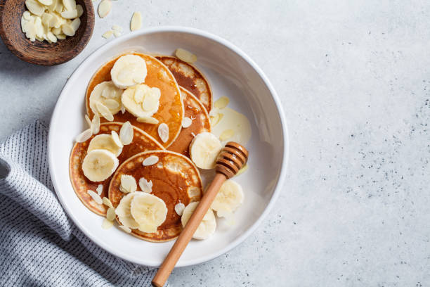 pancake tradizionali con banana, mandorle e miele in piatto bianco, vista dall'alto. - honey caramel syrup fruit foto e immagini stock