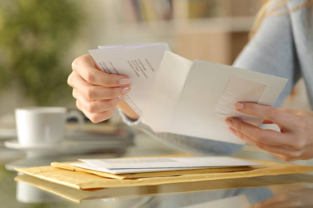 Girl hands opening an envelope on a desk at home Close up of girl hands opening an envelope with a letter inside on a desk at home sending photos stock pictures, royalty-free photos & images