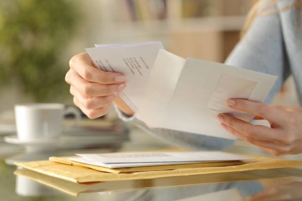 Girl hands opening an envelope on a desk at home Close up of girl hands opening an envelope with a letter inside on a desk at home post stock pictures, royalty-free photos & images