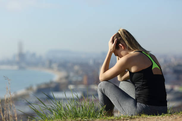 Frustrated runner sitting outdoors complaining Frustrated runner sitting outdoors complaining in the city outskirts a sunny day athlete fails stock pictures, royalty-free photos & images