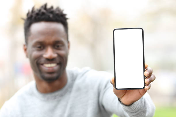 istock Happy black man showing phone screen mockup 1217020413