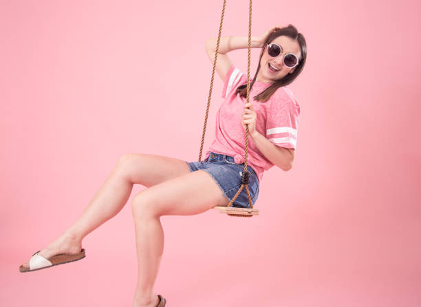 istock Young woman on a swing on a pink background. 1217020563