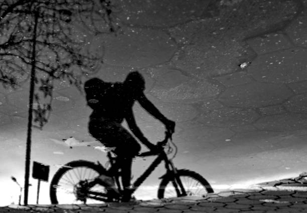 istock Cyclist with a reflection in a puddle after the rain, with trees in the water 1217021442