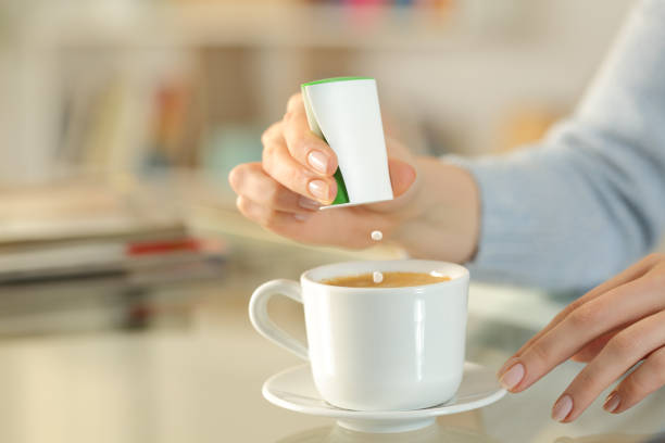 donna lancia a mano pillole di saccarina sulla tazza di caffè - pouring coffee human hand cup foto e immagini stock